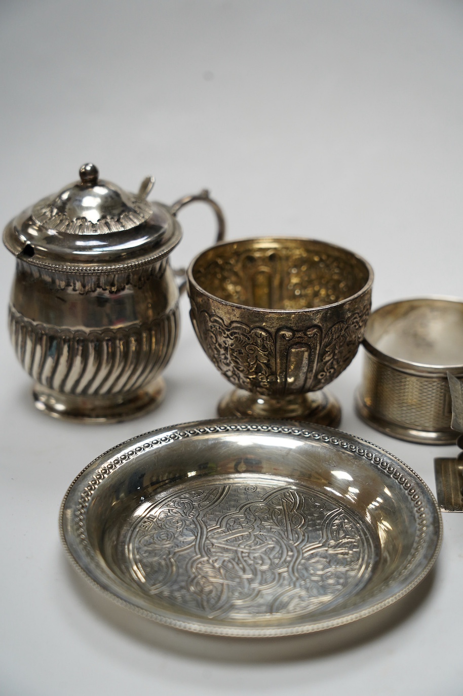 Sundry small silver including five silver napkin rings, and 800 napkin ring, a Victorian silver mustard and salt, an Egyptian small white metal dish, three silver condiment spoons and five plated items. Condition - poor